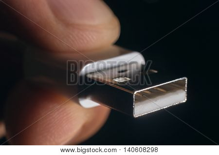 Hand holding white USB cable. Man's hand holds a USB Connector.
Closeup man hand holding USB cable.Selective focus and shallow Depth of field.