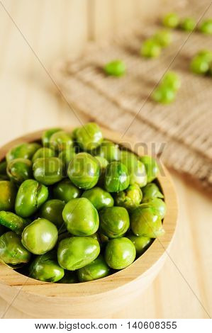 Peanut spiling out of a wooden bowl on blurred background