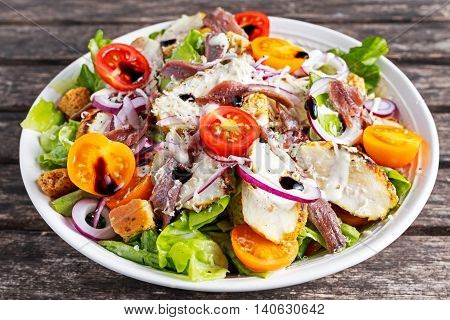 Ceasar salad with grilled chicken fillets, red onion rings, lettuce, orange cherry tomatoes, croutons, grated parmesan cheese, seasoned with anchovy fillets.