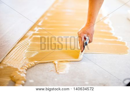 Close-up Of Hand Of Worker Adding Glue During Parquet Installation