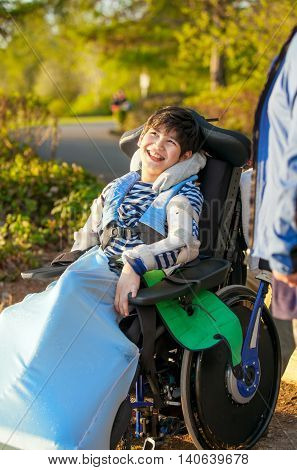 Smiling nine year old boy in wheelchair enjoying time at park outdoors