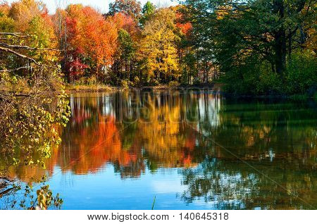 A tranquil pond reflects the colors of a late afternoon in autumn