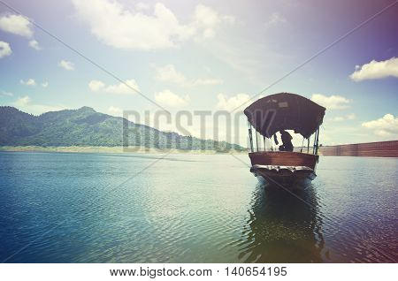 A fishing boat approaches shore area at Khun Dan dam Nakohn Nayok Thailand with light effect