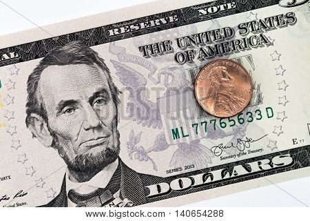 Five dollars banknote with a penny on it
