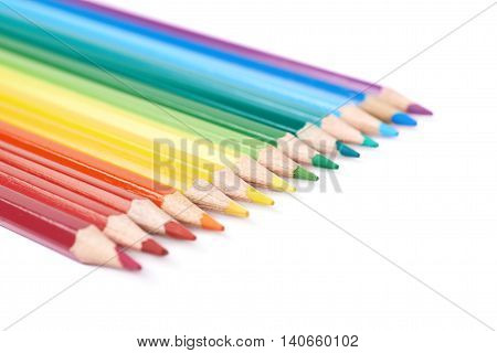 Multiple colorful color pencils composition arranged in a line to form a rainbow gradient, composition isolated over the white background, close-up crop fragment