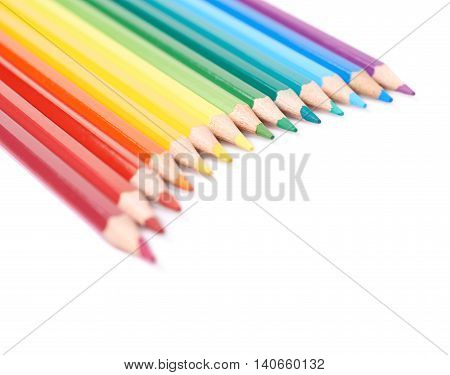Multiple colorful color pencils composition arranged in a line to form a rainbow gradient, composition isolated over the white background, close-up crop fragment
