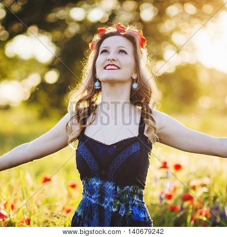 Beautiful young woman on the poppy field in sunlight