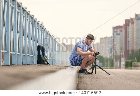 Man with photo camera on tripod taking timelapse photos in the city