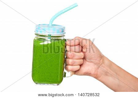 Human hand holding jar tumbler mug with green smoothie drink