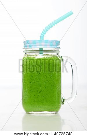 Jar tumbler mug with green smoothie drink over white