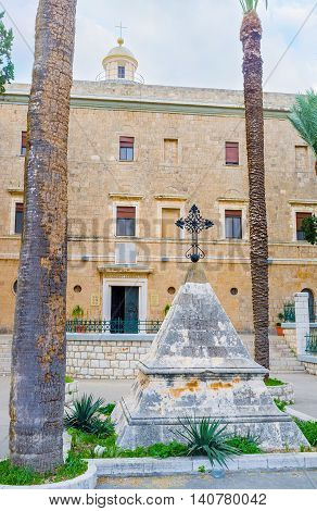 The small pyramid-shaped memorial stone with an iron cross on the top located in front of the Stella Maris Monastery Haifa Israel.
