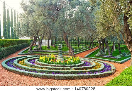 The round flower bed consists of many rows of colorful flowers with the Oriental park sculpture in the middle Bahai Gardens Haifa Israel.