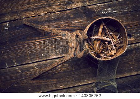 old rusty pinchers with can of nails on wooden boards background
