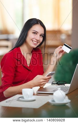 Young business woman holding mobile phone and credit card. Woman pays for a purchase with credit card. Purchase online. Shopping online