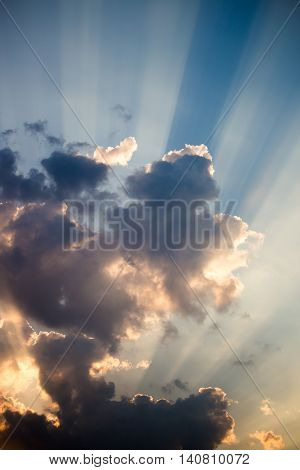 The sun's rays shine through the clouds in the evening