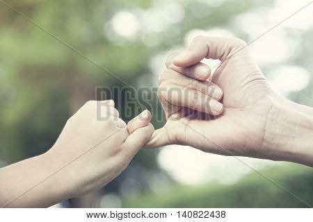 mother and her child hooking their fingers to make a promise