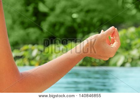 young woman meditating on the swimming pool