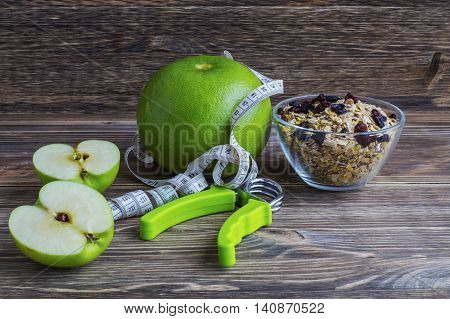 The concept of a healthy lifestyle. Green fruits oatmeal with raisins measuring tape and hand espander.