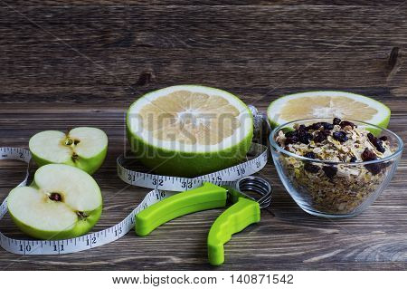 The concept of a healthy lifestyle. Green fruits oatmeal with raisins measuring tape and hand espander.