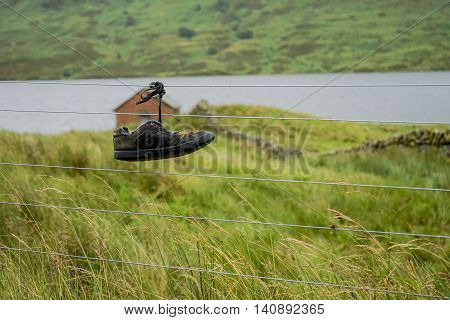 Abandoned and lost shoe tied up on a fence