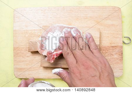 Chef putting flour to raw porkchop / cooking porkchop steak concept