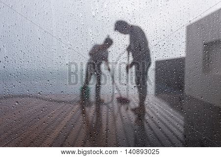Blurred People Washing Decking By Pressure Wash. Focus On Water Drop