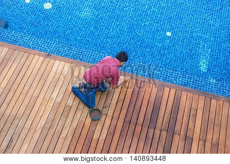 A Man Painting Exterior Wooden Pool Deck, Top View