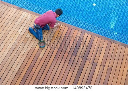A Man Painting Exterior Wooden Pool Deck, Top View