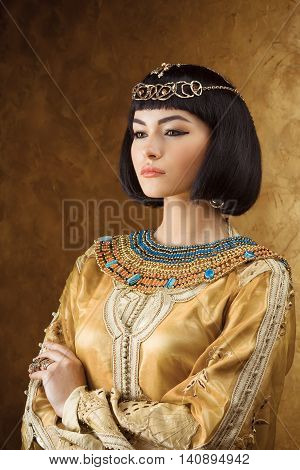 Photo of serious woman with Cleopatra makeup, closeup portrait of beautiful female with stylish haircut, young lady wearing fashionable golden necklace, beauty salon