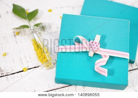 two gift boxes with heart shaped pin and plant in vase on white wood. Valentines day background. love romance concept