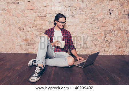 Young Man Sitting On Floor With Laptop And Drink Coffee