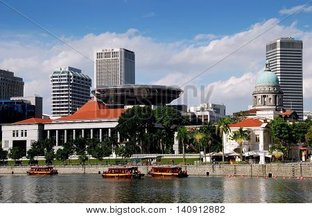 Singapore - December 28 2007: Singapore River touring boats the Singapore Parliament House (with orange roof) flying saucer shaped Supreme Sourt Building dome of the Old Supreme Court Building (green dome) and Raffles Landing Site