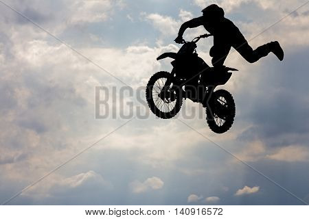 Jumping motorcircle rider silhouette on sky background.