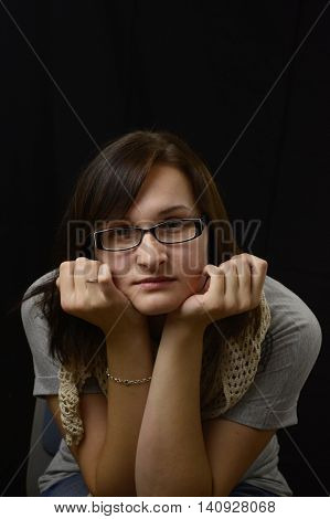 Philosophical pensive woman in glasses ponders and thinks having hands under chin.