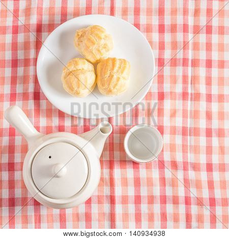 Eclair cream dessert in a dish on red and white chintz background.