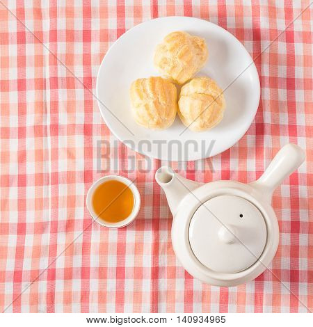 Eclair cream dessert in a dish on red and white chintz background.