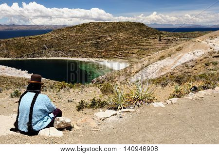 South America Bolivia - Isla del Sol on the Titicaca lake the largest highaltitude lake in the world. Woman siting in the traditional dress on the lake Titicaca