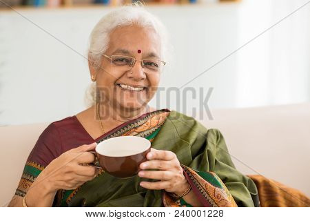 Happy Elderly Indian Woman In Traditional Dress Having A Cup Of Tea
