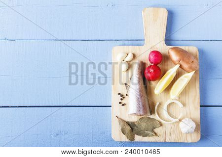 Fish, Lemon, Onion, Garlic, Radich And Seasoning On Cutting Board. Top View On Wooden Table With Cop