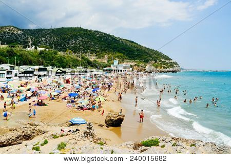 SITGES, SPAIN - JULY 9, 2017: People enjoying, relaxing, sunbathing or bathing at the Garraf Beach in Sitges, a popular beach in the coast of the Metropolitan Area of Barcelona, in Catalonia