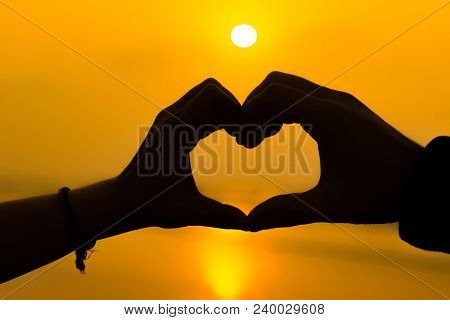 Couple Hands Making A Heart Love Sign Sillhoute During Sunrise At A Beach