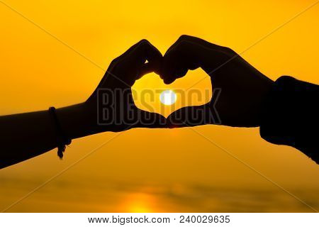 Couple Hands Making A Heart Love Sign Sillhoute During Sunrise At A Beach