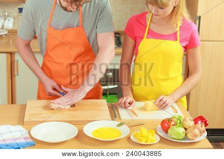Food Preparing, Couple Cooking In Kitchen. Man Cutting Raw Chicken Meat Breast On Wooden Board, Woma