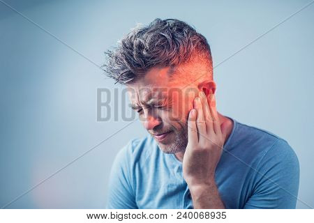 Male Having Ear Pain Touching His Painful Head Isolated On Gray Background