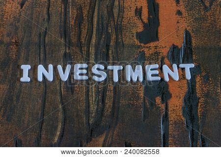 Investment Written In White Lettering On Weathered Dark Wood