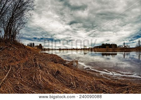 The Dramatic Sky Reflects On The River Water At The Northern Finland. The Nature Has Not Woken Up Ye