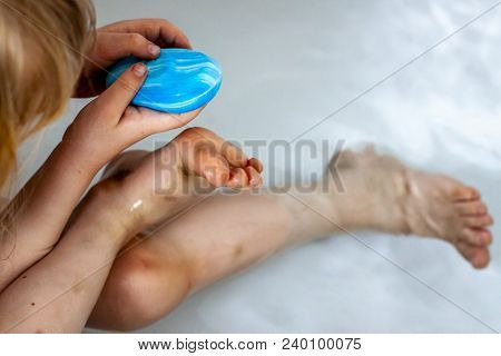 Little Girl Cleaning Her Dirty Feet In The Bathtub