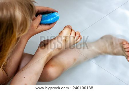 Little Girl Cleaning Her Dirty Feet In The Bathtub