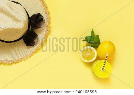 Straw Beach Foman's Hat And Black Sun Glasses With Citrics Water On Yellow. Top View. Flat Lay.