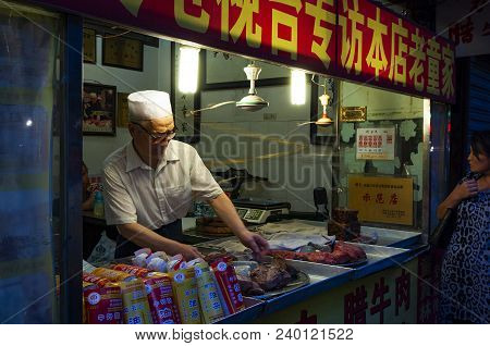 Xian, China - August 5, 2012: Man Selling Foof At A A Food Stall In A Street Of The Muslim Quarter I